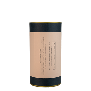 A navy blue cylinder with a pink label describes the espresso coffee beans within.