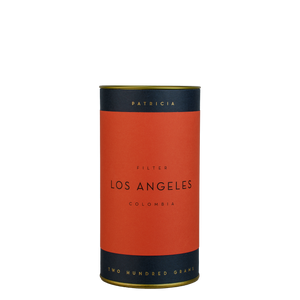 A navy blue cylinder with a red label describes the roasted coffee beans within. 'PATRICIA' and 'TWO HUNDRED GRAMS' are printed in gold foil.