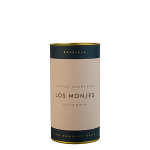 A navy blue cylinder with a pink label describes the espresso coffee beans within. 'PATRICIA' and 'TWO HUNDRED GRAMS' are printed in gold foil.