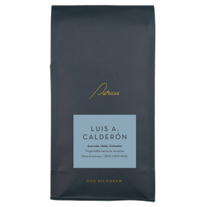 A navy blue recyclable bag containing 1kg of specialty coffee beans. It has the Patricia logo in gold, the coffee's name on a blue sticker, and 'One kilogram' in gold underneath.