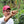 Luis A. Calderón in a coffee plantation holding a red coffee cherry, wearing a pink cap with 'Cofinet' branding.