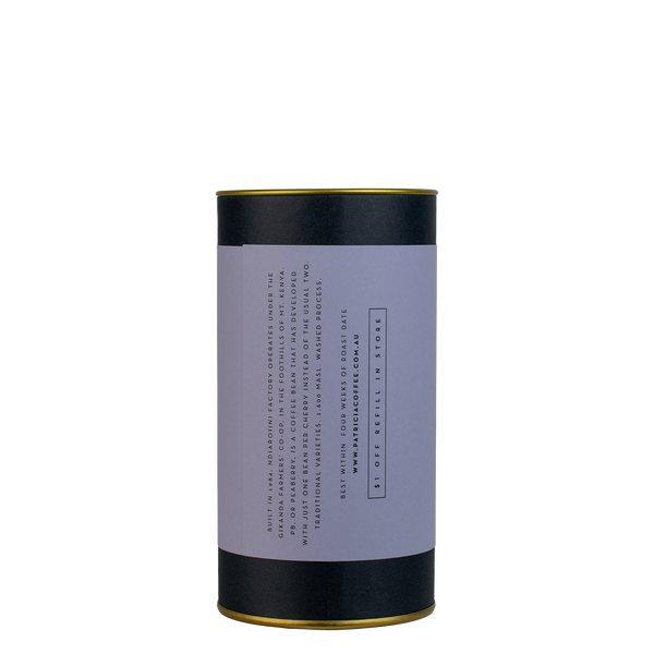 A navy blue cylinder with a purple label describes the roasted coffee beans within.