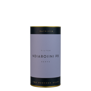 A navy blue cylinder with a purple label describes the roasted coffee beans within. 'PATRICIA' and 'TWO HUNDRED GRAMS' are printed in gold foil.