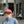 Person wearing a red running cap with a pink P on the front, outside Patricia Coffee Brewers