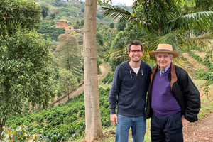 Pedro Echavarria Sr and Jr standing on a path overlooking many coffee trees in a valley.