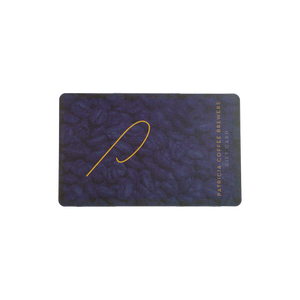 A rectangular Patricia Coffee Brewers gift card with a dark textured background, featuring a gold stylized logo and vertical gold text reading 'PATRICIA COFFEE BREWERS GIFT CARD' on the right side.