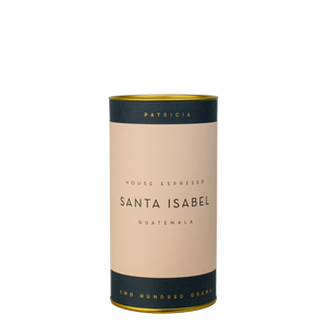 A navy blue cylinder with a pink label describes the espresso coffee beans within. 'PATRICIA' and 'TWO HUNDRED GRAMS' are printed in gold foil.
