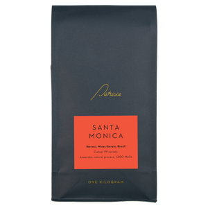 A navy blue recyclable bag containing 1kg of specialty coffee beans. It has the Patricia logo in gold, the coffee's name on a red sticker, and 'One kilogram' in gold underneath.