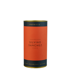 A navy blue cylinder with a red label describes the roasted coffee beans within. 'PATRICIA' and 'TWO HUNDRED GRAMS' are printed in gold foil.
