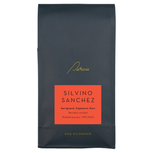 A navy blue recyclable bag containing 1kg of specialty coffee beans. It has the Patricia logo in gold, the coffee's name on a red sticker, and 'One kilogram' in gold underneath.