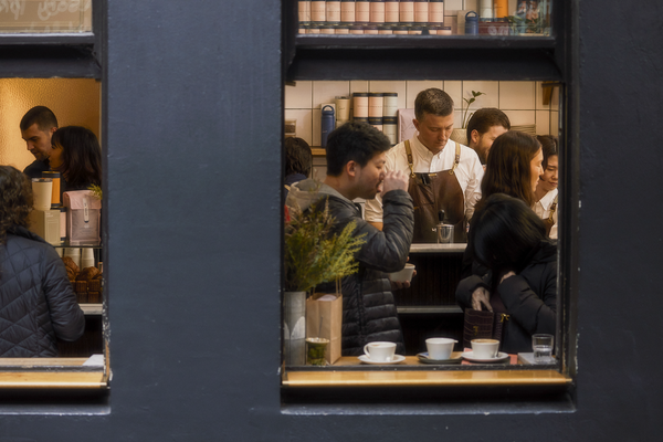 Busy cafe filled with customers, baristas, coffee equipment and specialty-coffee beans.