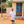 Ture Waji stands outside a building with colourful plastic stools surrounding him.