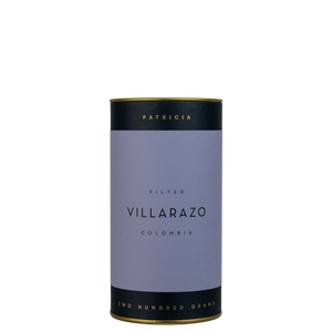 A navy blue cylinder with a purple label describes the filter coffee beans within. 'PATRICIA' and 'TWO HUNDRED GRAMS' are printed in gold foil.