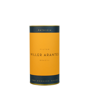 A navy blue cylinder with an orange label describes the roasted coffee beans within. 'PATRICIA' and 'TWO HUNDRED GRAMS' are printed in gold foil.