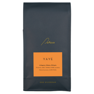 A navy blue recyclable bag containing 1kg of specialty coffee beans. It has the Patricia logo in gold, the coffee's name on an orange sticker, and 'One kilogram' in gold underneath.